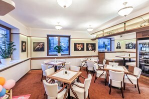 Un hall d’hôtel doté de plusieurs espaces aménagés avec des sièges, d’un comptoir de réception et d’œuvres d’art accrochées aux murs.