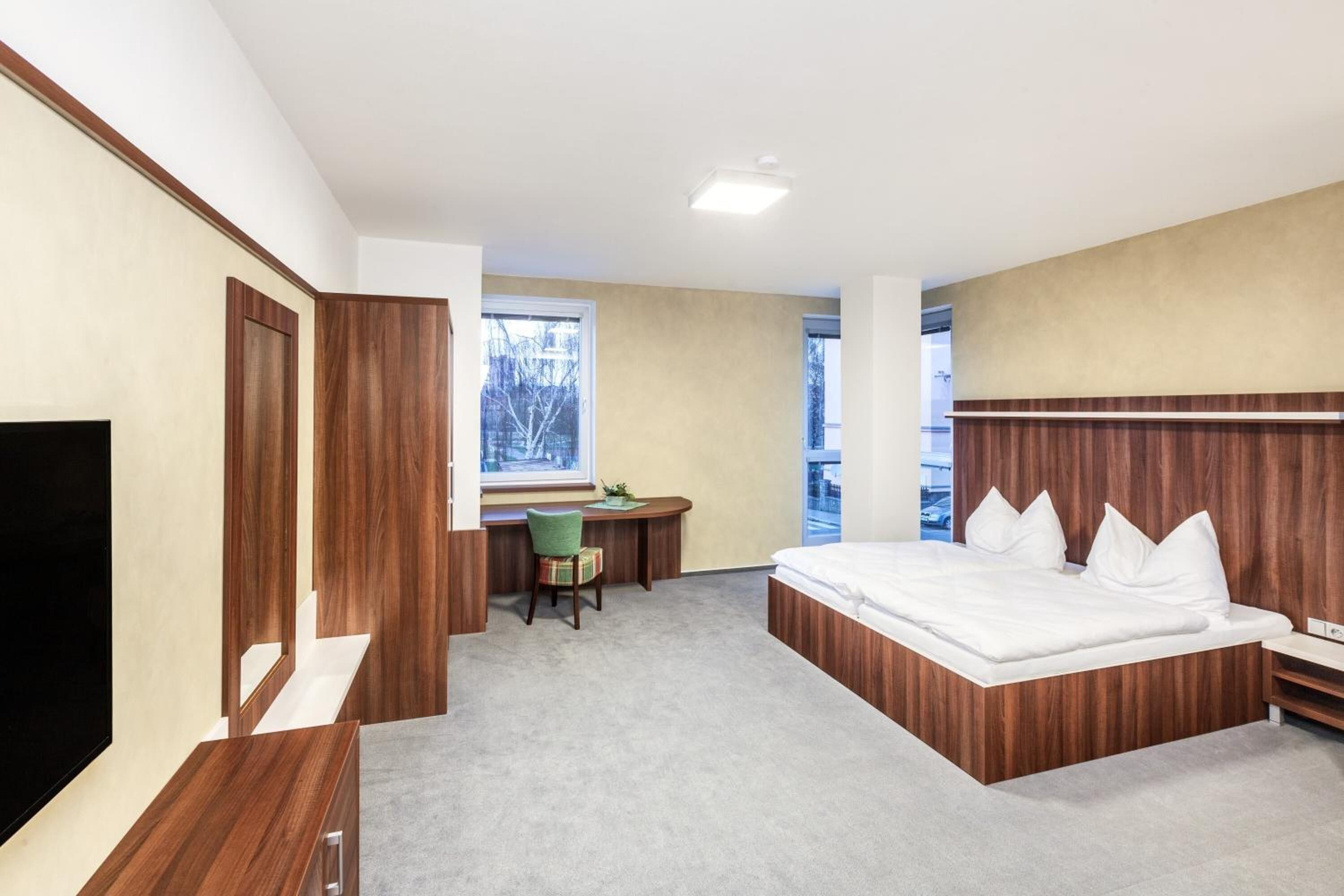 A modern hotel room with a large bed, a desk, and a TV.