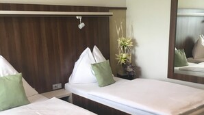 A hotel room with two single beds, a wooden headboard, a nightstand, a mirror, and a vase with flowers. - Graphic Hotel Novy Jicin (Novy Jicin)