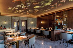 A restaurant with a bar area, tables with chairs, and a ceiling mural. - Ca di Dio (Venice)