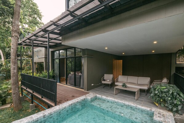 Ein moderner Poolbereich im Freien mit einer Holzterrasse, einer Sitzecke und einem Couchtisch.