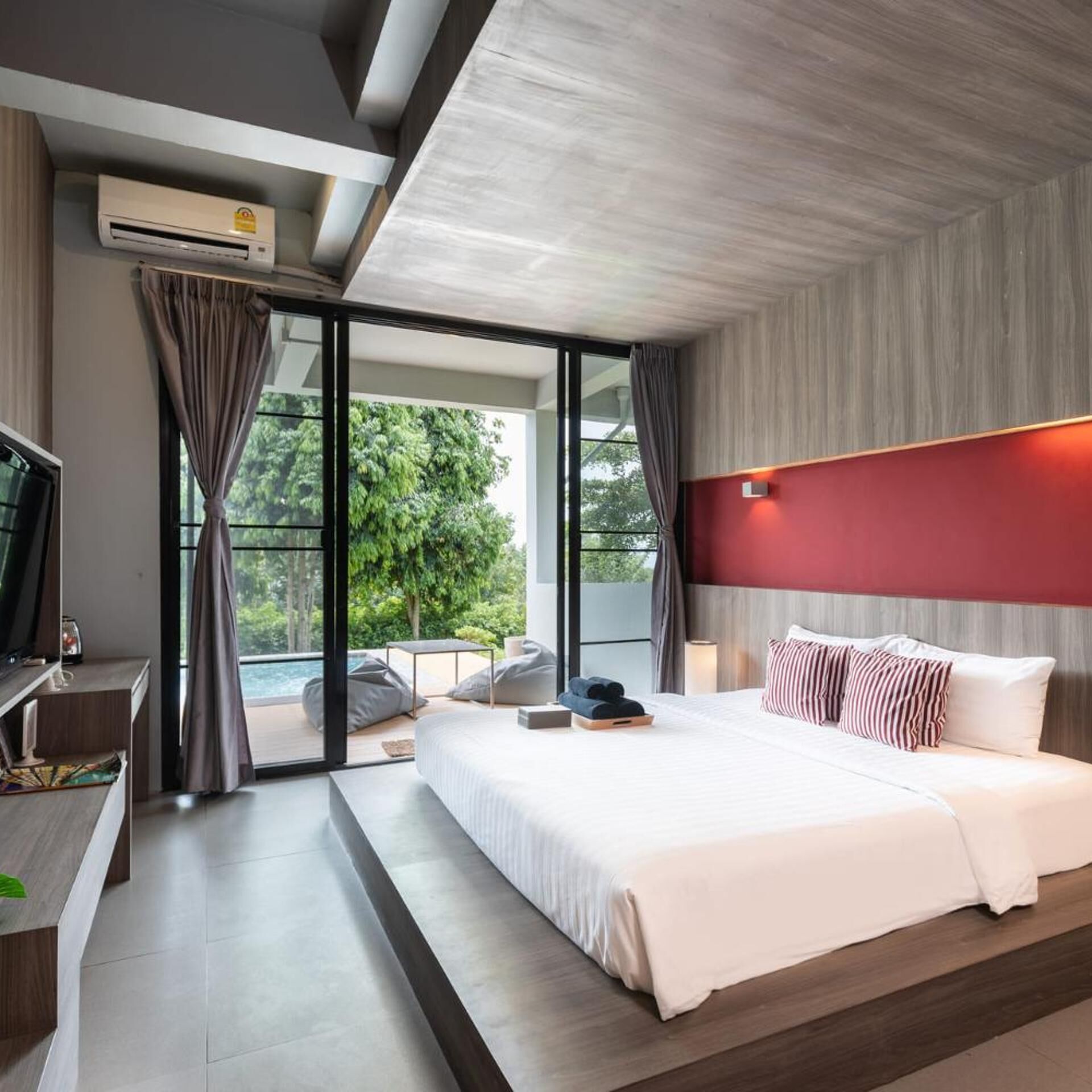 Ein modernes Hotelzimmer mit einem großen Bett, einem Fernseher und Blick ins Freie.