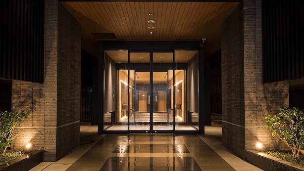 A modern building entrance with glass doors, a tiled floor, and wooden paneling. - Tmark City Hotel Kanazawa (Kanazawa)