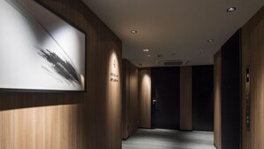 A hallway with wooden paneling, a framed abstract painting, and a carpeted floor. - Tmark City Hotel Kanazawa (Kanazawa)