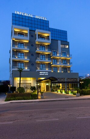 Un hôtel à plusieurs étages, doté d’une façade moderne, de balcons et d’une entrée bien éclairée.