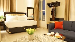 A hotel room with a bed, a sofa, a coffee table with breakfast items, a mirror, and a window with curtains. - D Primahotel Pattimura Makassar (Makassar)