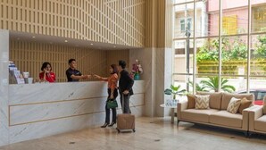 A hotel reception area with a marble counter, a reception desk, a sofa, and a large window with a view of greenery outside. - D Primahotel Pattimura Makassar (Makassar)