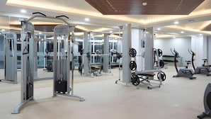 Une salle de sport équipée de divers appareils d’exercice, de miroirs et dotée d’un plafond en bois.
