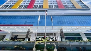 Un bâtiment moderne doté d’une façade en verre, d’une entrée imposante surmontée d’un auvent, et dont le nom, « CENTRO PAPUA », est clairement visible sur la façade.
