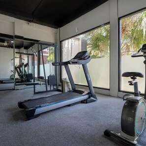 Un gimnasio con cinta de correr, bicicleta estática y equipo de ejercicio.