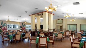 A spacious dining area with multiple tables and chairs, large pillars, and hanging chandeliers. - Mystic Valley Spa Resort (Igatpuri)