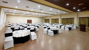 A large conference room with rows of round tables and chairs, equipped with ceiling lights and a wooden ceiling. - Mystic Valley Spa Resort (Igatpuri)