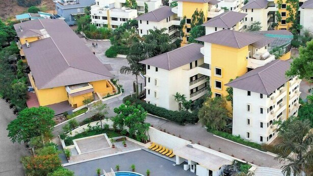 A residential area with multiple two-story buildings, a central swimming pool, and surrounding greenery. - Mystic Valley Spa Resort (Igatpuri)