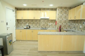 A kitchen with light wooden cabinets, a granite countertop, a built-in stove, and a sink. - Uptown Apartments by Gewan (Al-Fujairah)