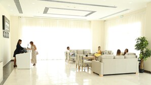 Un vestíbulo de hotel con mostrador de recepción, zona de estar y un amplio ventanal.