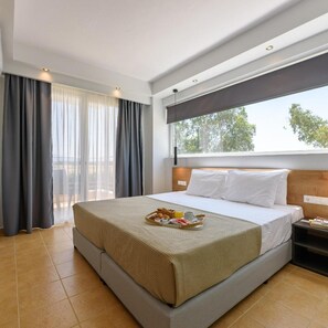 Quarto de hotel com uma cama grande, janela com cortinas, mesa de cabeceira e bandeja com itens de café da manhã.
