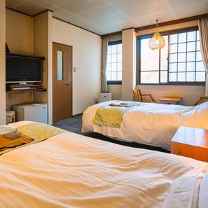 A hotel room with two beds, a television, a desk, and a window with curtains. - Hotarunoyado Sendou (Yufu)
