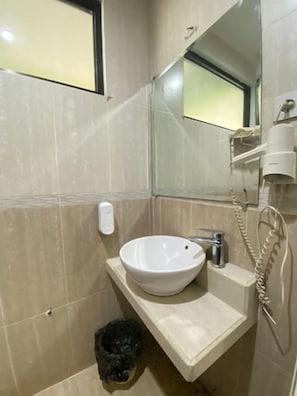 Een badkamer met een witte wastafel, een spiegel, een handdoekhouder en een prullenbak.