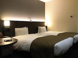 A hotel room with a bed, bedside tables, and a wall-mounted light fixture.