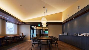 A conference room with a long table, chairs, a hanging light fixture, and a counter with items on it.