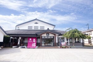 A hotel entrance with a large sign, a covered walkway, and a tree in front.