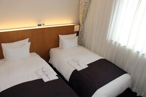 Ein Hotelzimmer mit zwei Betten, einem Nachttisch, einer Uhr und einem Fenster mit Vorhängen.