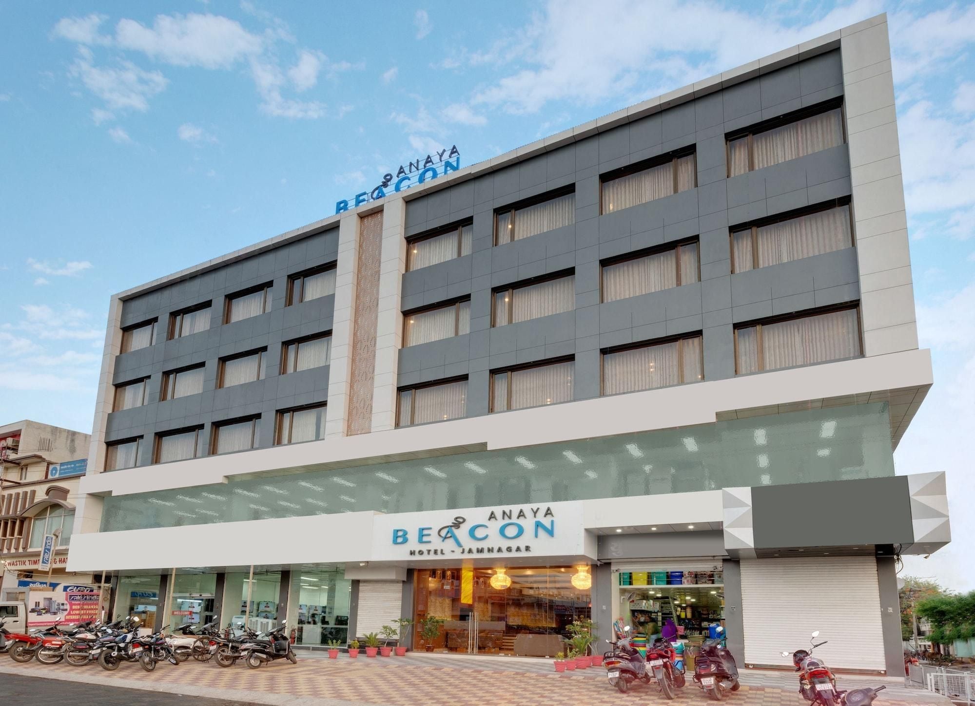 Ein mehrstöckiges Hotelgebäude mit einem Schild, auf dem 'BEACON HOTEL JAMNAGAR' steht.