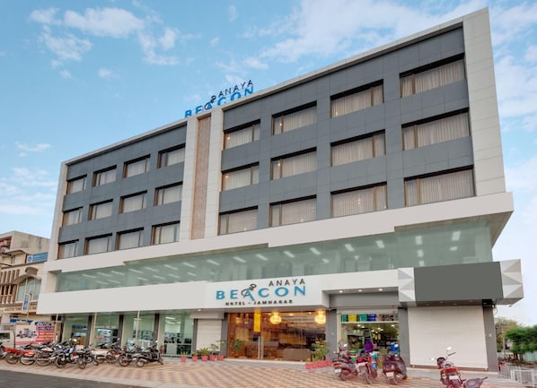 Un immeuble d’hôtel à plusieurs étages, sur lequel on peut lire l’inscription « BEACON HOTEL JAMNAGAR ».