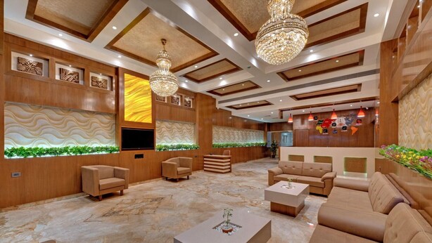 A spacious lobby with a marble floor, wooden paneling, and a large chandelier. - Anaya Beacon Hotel (Jamnagar)