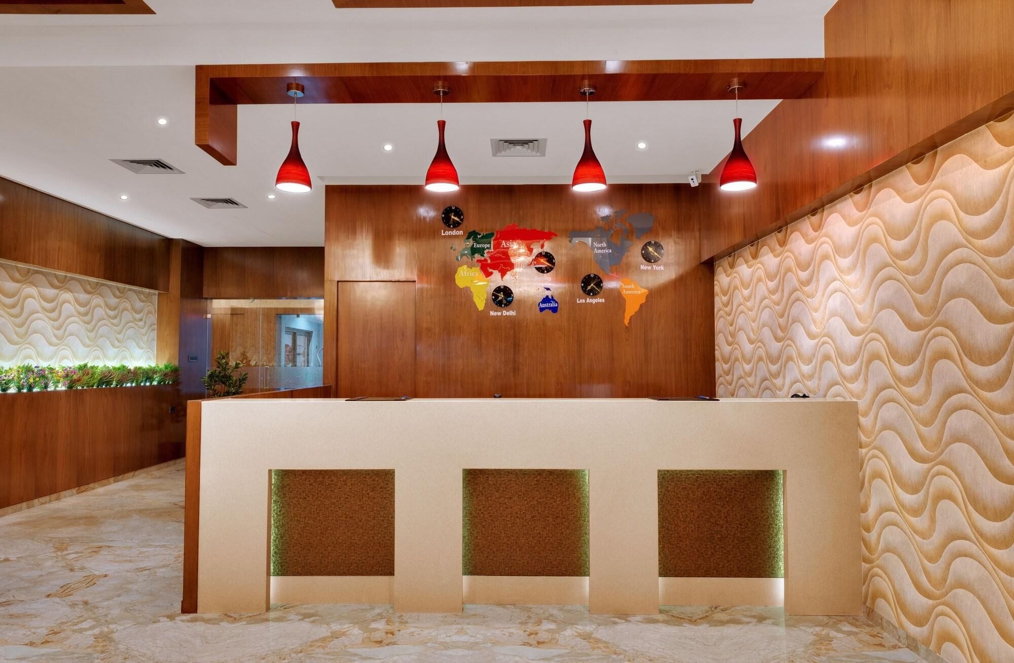 Een hotel receptie met een houten balie, een wereldkaart en rode hanglampen.