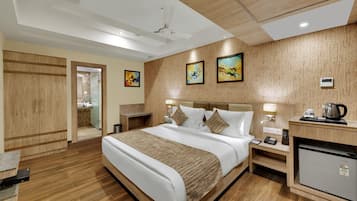 Habitación de hotel con cama, mesitas de noche, escritorio, refrigerador y obras de arte en las paredes.