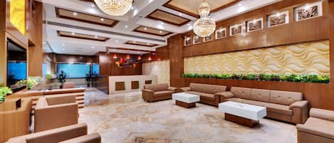 A lobby with a reception desk, sofas, a coffee table, and a decorative wall.