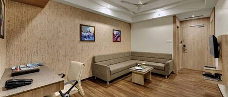 A modern office with a desk, chair, sofa, and a ceiling fan.
