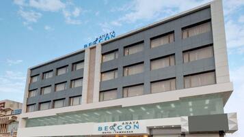 Un hotel de varios pisos con un diseño moderno, que presenta un llamativo letrero 'Beacon' en la entrada.