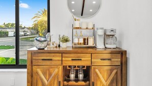 Un meuble en bois avec un miroir, une machine à café et une étagère avec des bouteilles et un vase.