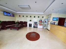 Un hall de hotel con mostrador de recepción, zona de estar, pantallas de televisión y chimenea.