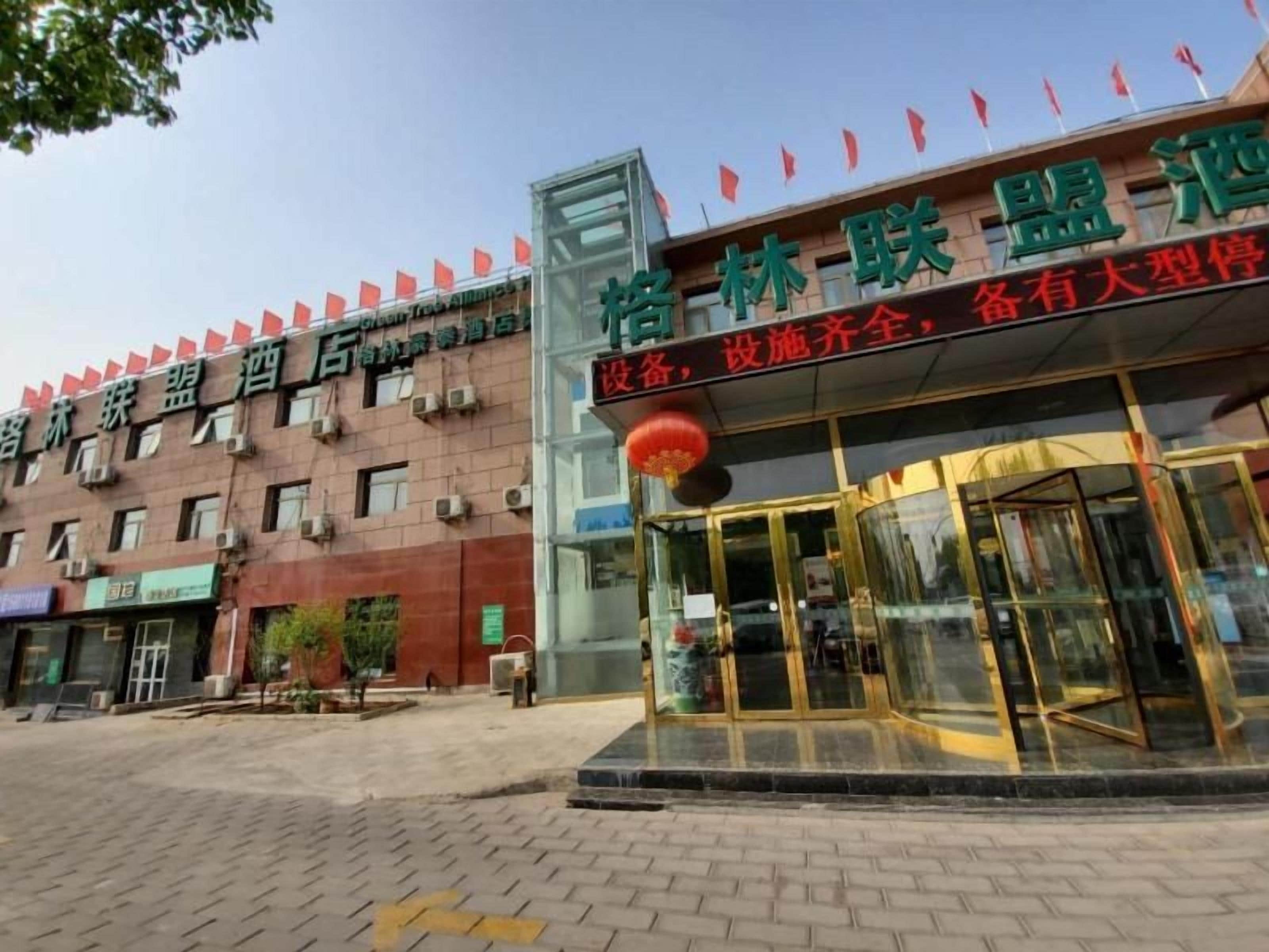 A hotel entrance with a glass facade, a red lantern, and a signboard with Chinese characters.