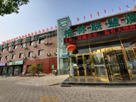 Entrada de hotel con fachada de vidrio, un farol rojo y un cartel con caracteres chinos.