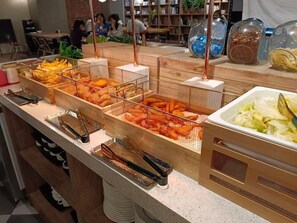 Ein Buffet mit verschiedenen Speisen in Drahtkörben, darunter Pommes, Gemüse und weitere Gerichte.