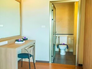 Un bany amb vàter, un lavabo amb mirall i una cadira.