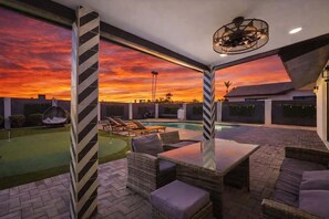 An outdoor patio with a pool, lounge chairs, and a table. - Glimmer-Sparkling Pool & Mini Golf-Near Old Town (Scottsdale)