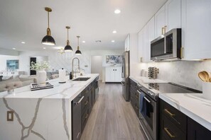 A modern kitchen with a central island, stainless steel appliances, and pendant lighting. - Glimmer-Sparkling Pool & Mini Golf-Near Old Town (Scottsdale)