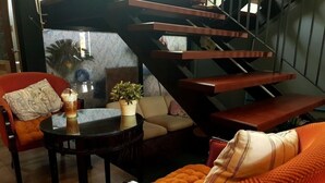 A modern living room with a sofa, a coffee table, and a staircase. - Iresidence Hotel Pathumthani (Khlong Luang)