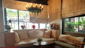 A cozy living area with a beige sofa, a small round table with a plant, and a red chair. - Iresidence Hotel Pathumthani (Khlong Luang)