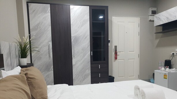 A bedroom with a bed, a wardrobe, a door, and a small table with a plant. - Iresidence Hotel Pathumthani (Khlong Luang)