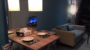 A dining area with a table set for two, a sofa, and a television in the background. - Atlantis Condo Resort Pattaya EVT (Pattaya)