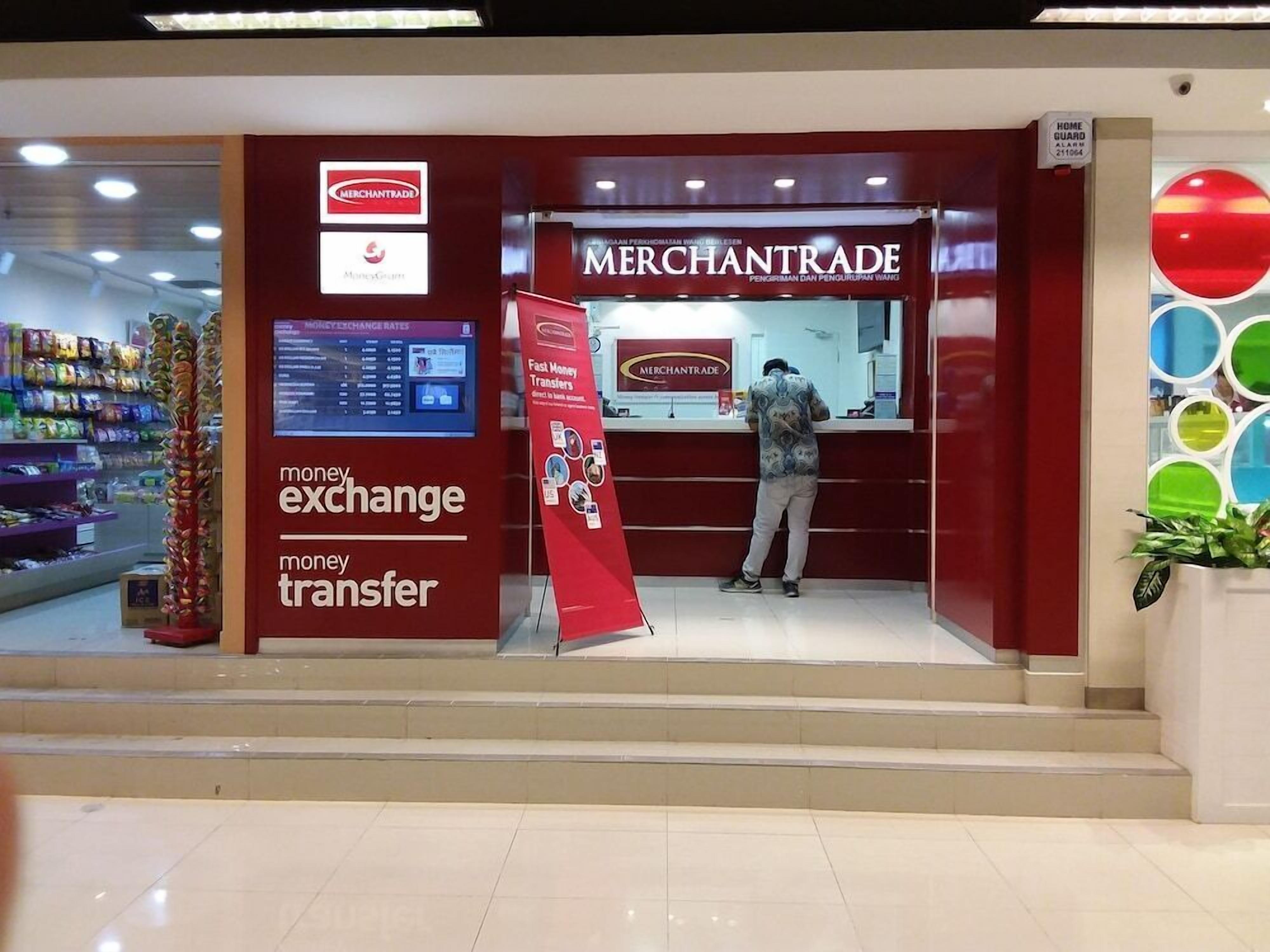 Un quiosco de cambio de divisas de MercanTrade con un panel que muestra los tipos de cambio digital y un hombre utilizando el servicio.