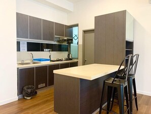 A modern kitchen with dark cabinetry, a central island, and a built-in stove. - Sunset & Seaview Vacation Condo City Centre @ Imago Shopping Mall (Kota Kinabalu)