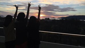 A group of people silhouetted against a sunset with their arms raised. - Sunset & Seaview Vacation Condo City Centre @ Imago Shopping Mall (Kota Kinabalu)