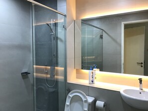 A modern bathroom with a glass shower enclosure, a toilet, a sink, and a mirror above the sink. - Sunset & Seaview Vacation Condo City Centre @ Imago Shopping Mall (Kota Kinabalu)